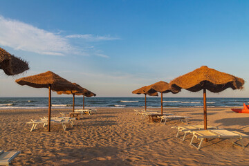 Sun umbrellas and chaise lounges on tropical beach. Concept of rest, relaxation, holidays, resort