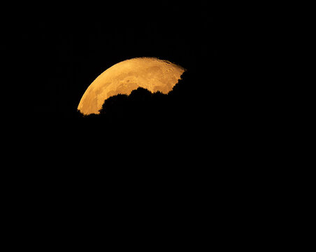 Aerial view of the moon partially obscured by dark clouds, shrouded in mystery and golden light, space. Monte Bre, Lugano, Switzerland