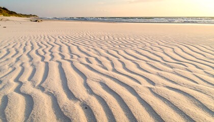 Rippled sand patterns on a beach at sunset, with ocean waves in the distance