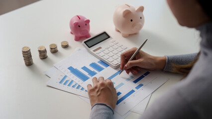 Financial Analysis: Woman Writing on Graphs with Piggy Banks Nearby