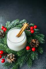 Festive creamy winter drink with cinnamon stick in evergreen wreath decoration