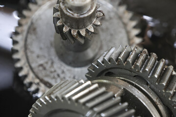 Close up of interlocking metal gears, conveying sense of industrial complexity and mechanical function. These intricate components, showing signs of wear and operation, represent inner workings