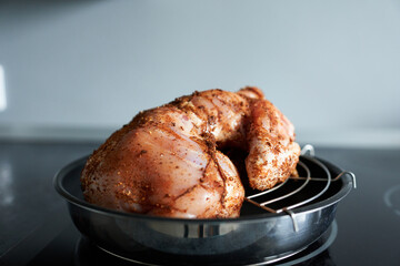 Raw chicken in spices on an induction cooker in the kitchen.
