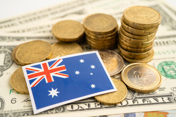 Stack of coins with Australia flag and US dollar banknotes.