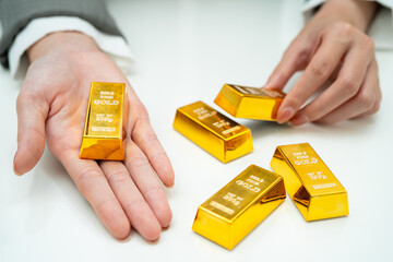 Asian woman holding gold bar in finance business.