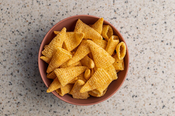 Bugles snack. Cone corn chips in bowl on kitchen table. Top view.
