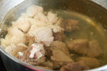 Boiled turkey thigh in a saucepan with broth.