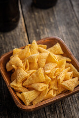 Bugles snack. Cone corn chips in bowl on wooden table.
