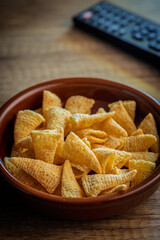 Bugles snack. Cone corn chips in bowl on wooden table.