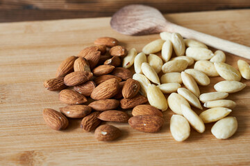 Almond nuts and wooden spoon on wooden background. Healthy food.