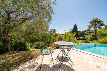 Terrasse ensoleillée avec table de jardin et piscine méditerranéenne
