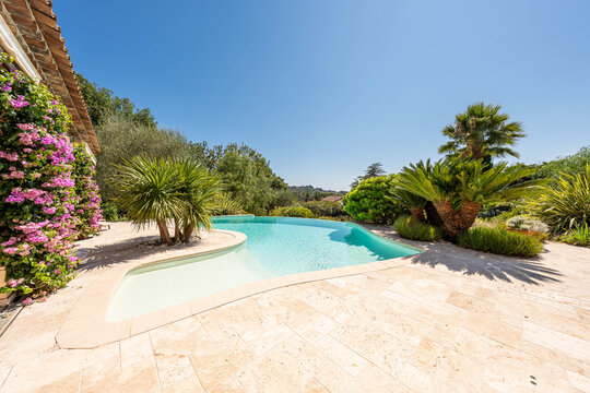 Luxury Mediterranean villa garden with swimming pool and palm trees &mdash; summer holiday atmosphere in the French Riviera