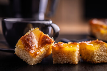 Catalana sponge cake and coffee cup on black table.