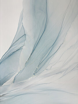 Abstract light blue aquarelle art background. Beautiful watercolor stains made with alcohol ink. Blue with beige and gold fluid art bird or angel wings, natural texture resembles sky, smoke, air.