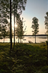 Romantic sunset on the lake with boat, jetty and forest silhouettes