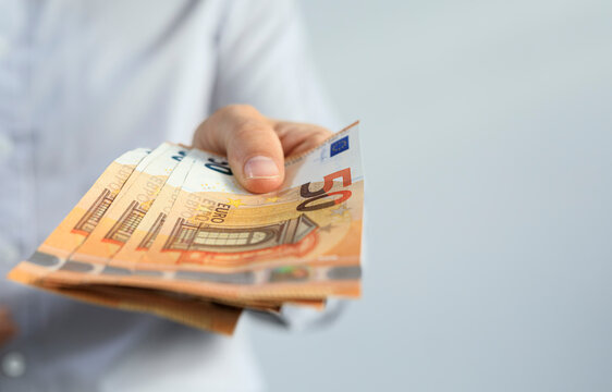 Close-up of a hand giving out several fifty euro banknotes.  Financial transaction concept.