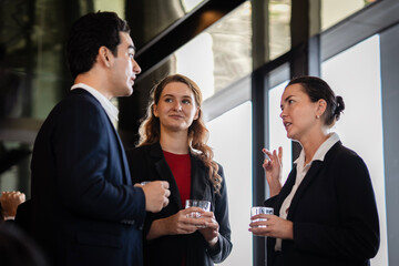 Business people interacting during an after-hours gathering, representing collaboration, leadership, and partnership in a relaxed corporate environment. Employee enjoy talking at party.