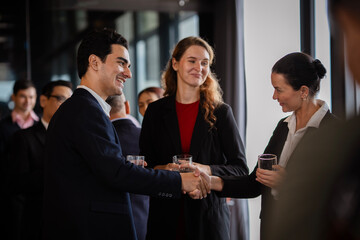 Professional man and woman greeting each other with a handshake during an offsite business meeting party, representing teamwork, leadership, and successful collaboration.