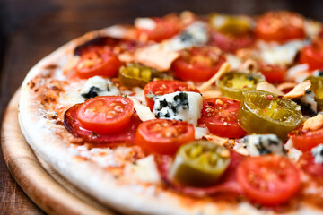 Pizza with salami, jalapeno pepper, cherry tomatoes and mozzarella cheese. Soft focus.	