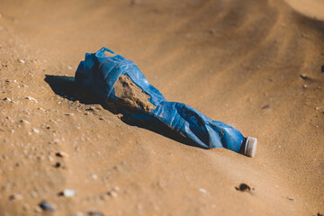 bottiglia di plastica blu accartocciata e vecchia abbandonata su una spiaggia. concetti sull'inquinamento ambientale da plastica