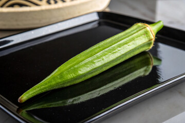 Green ridge gourd on black plate
