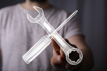 Image of a hand holding a digital drawing of a wrench and screwdriver, symbolizing repair,...