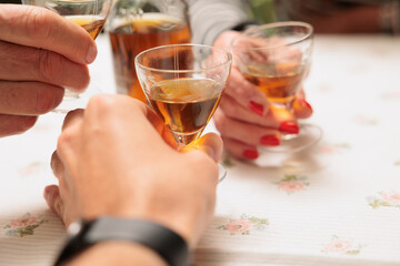 vista macro di pani di persone caucasiche che fanno un brindisi con dei piccoli bicchieri da cocktail