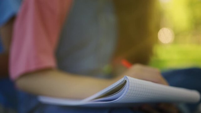 Teen girl writing thoughts in diary while resting in park, first love emotions