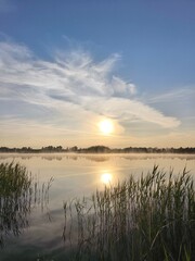 Magical golden sunrise above a misty lake, where thick fog drifts across the water in a dreamy, tranquil morning atmosphere.