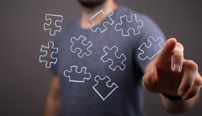 Abstract concept image showing a man connecting puzzle pieces, symbolizing problem-solving, teamwork, and strategy.