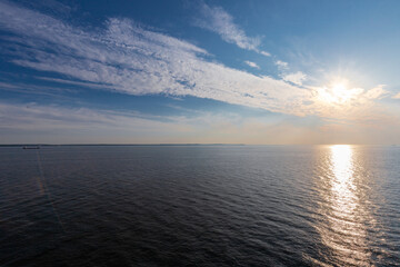 Fototapeta premium Beautiful sunset full of amazing natural colours seen over the North Sea during the summer solstice in Scandinavia, with the clouds creating a unique idyllic painting with reflections in the ocean