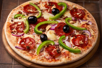 Pizza with chorizo ​​sausage, mozzarella cheese, green pepper and black olives. Rustic wooden background. Soft focus.	