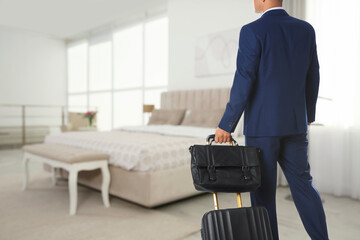 Businessman with suitcase and bag in hotel room. Guest heading to bed