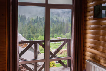 Panoramic window in mountain house with wood-paneled walls