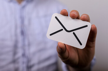 High-quality image of a hand holding an email icon card, perfect for websites and marketing materials. Represents communication, contact,