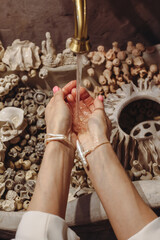Young woman washes hands at a unique seashell-decorated washbasin with pearl beads