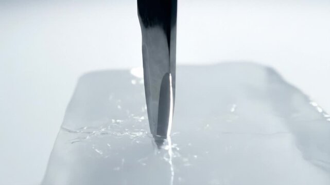 Sharp metal chisel breaking clear ice block with precision