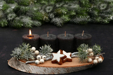 Arrangement for the first Advent with text space: Natural Advent decoration with brown candles, cinnamon stars and fir branches in the background.