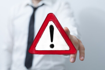 A professional's hand displays a digital red triangular warning sign with an exclamation mark, symbolizing caution, danger, and important alerts