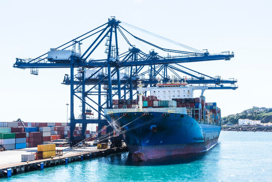 Cargo container ship under gantry cranes in the San Antonio port, Chile. She is loaded with cargo in the containers. 