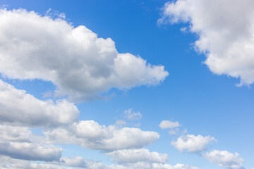 Obraz premium White clouds on a summer blue sky for background or wallpaper design. Majestic cumulus clouds float across the endless sky, their graceful forms painting a mesmerizing canvas of beauty and grandeur.