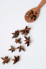 Close-up of dried star anise in a wooden spoon isolated on white background