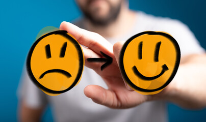 Stock photo depicting a hand changing a sad face into a happy one. Perfect for articles on...