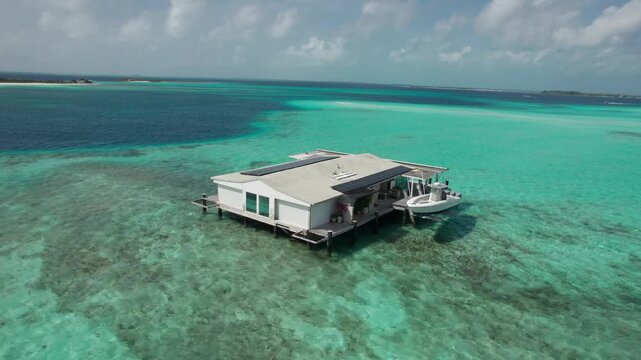 Aerial orbital shot of a tranquil house on stilts in the stunning turquoise waters of Los Roques, Venezuela.