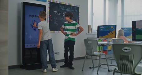 Schoolboy Uses Interactive Digital Screen, Talks Classmate. Boys Study STEM Classroom. Concept Of Integrating Educational Technologies, Social-emotional Learning Into Modern Education. Dolly Shot.