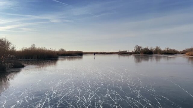 Point Of View ice skating on a frozen lake in nature during a beautiful winter day in Holland.