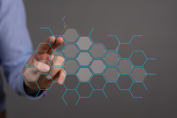 Abstract technology concept.  Hand touches futuristic hexagon grid.  Digital innovation, connection, network.