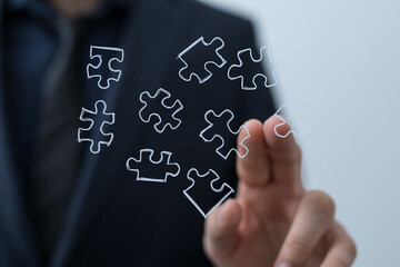 Abstract image of a businessman connecting puzzle pieces, symbolizing solutions, strategy, and teamwork.