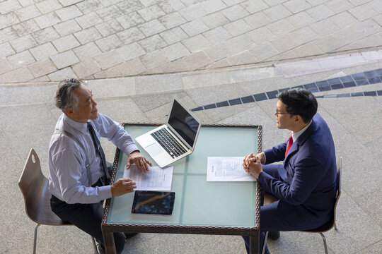 Two generations of business professionals in a modern setting conduct a recruitment interview, highlighting young talent, mentorship, and intergenerational collaboration for success.