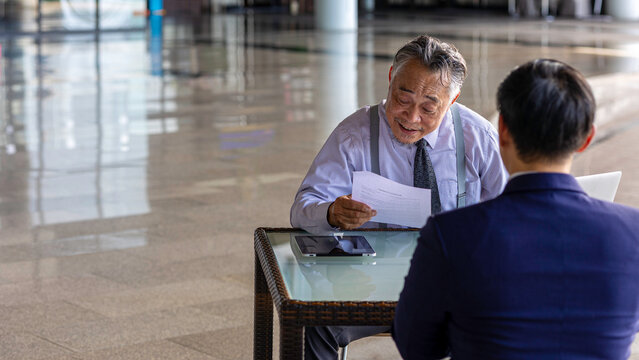 Two generations of business professionals in a modern setting conduct a recruitment interview, highlighting young talent, mentorship, and intergenerational collaboration for success.